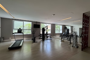 Un gimnasio moderno con equipamiento cardiovascular, máquinas de pesas y un muro de espejos.