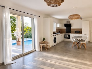 A modern kitchen with a dining area, a washing machine, and a view of a swimming pool. - New house with private pool (Ruoms)