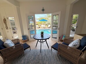 A room with a pool, wicker furniture, and a view of the outdoors.