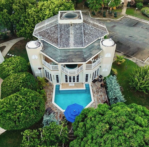 A large, multi-story building with a central swimming pool, surrounded by lush greenery.