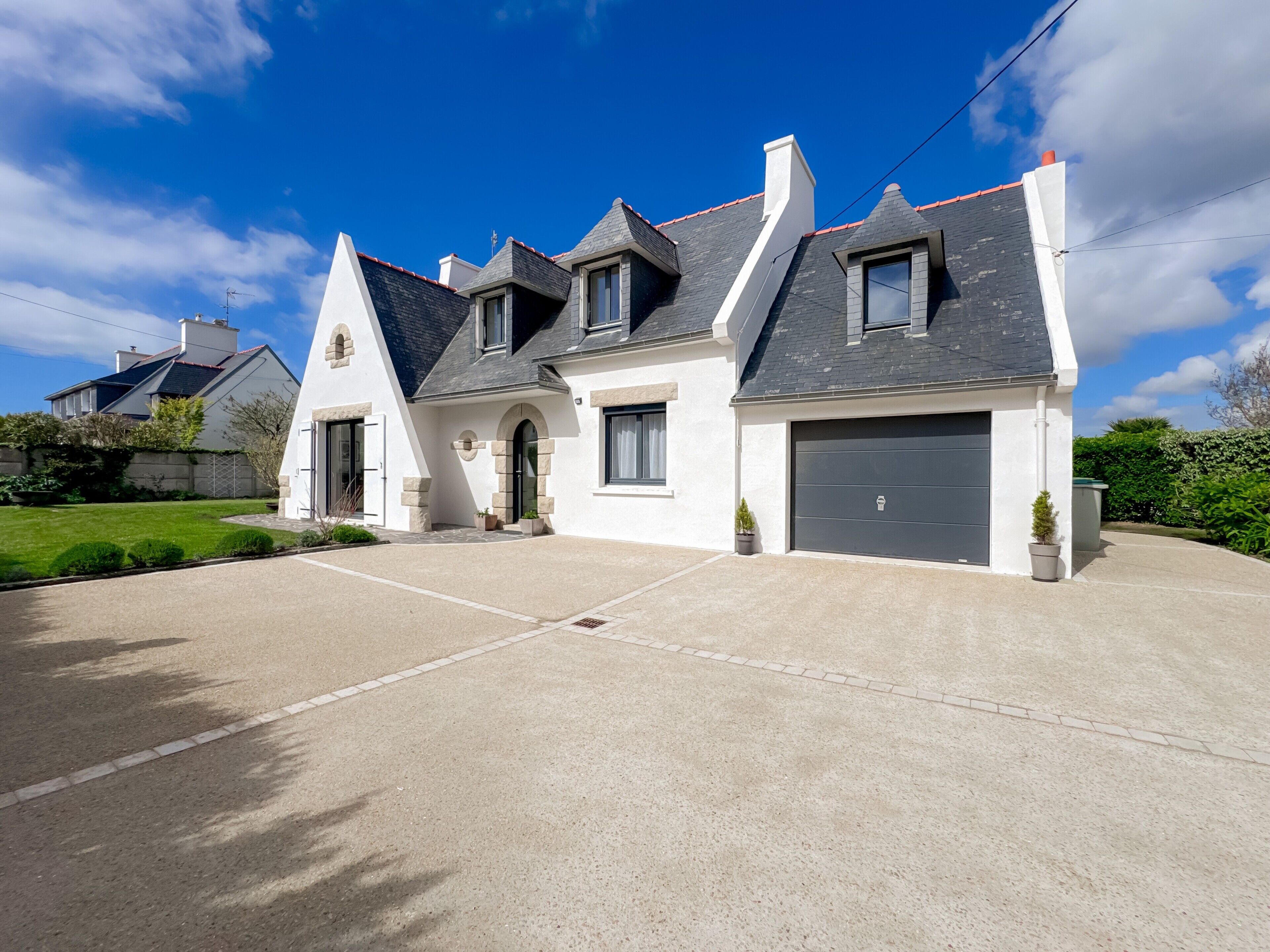 Une maison moderne à deux étages, dotée d’un garage, d’une allée et d’une pelouse bien entretenue.