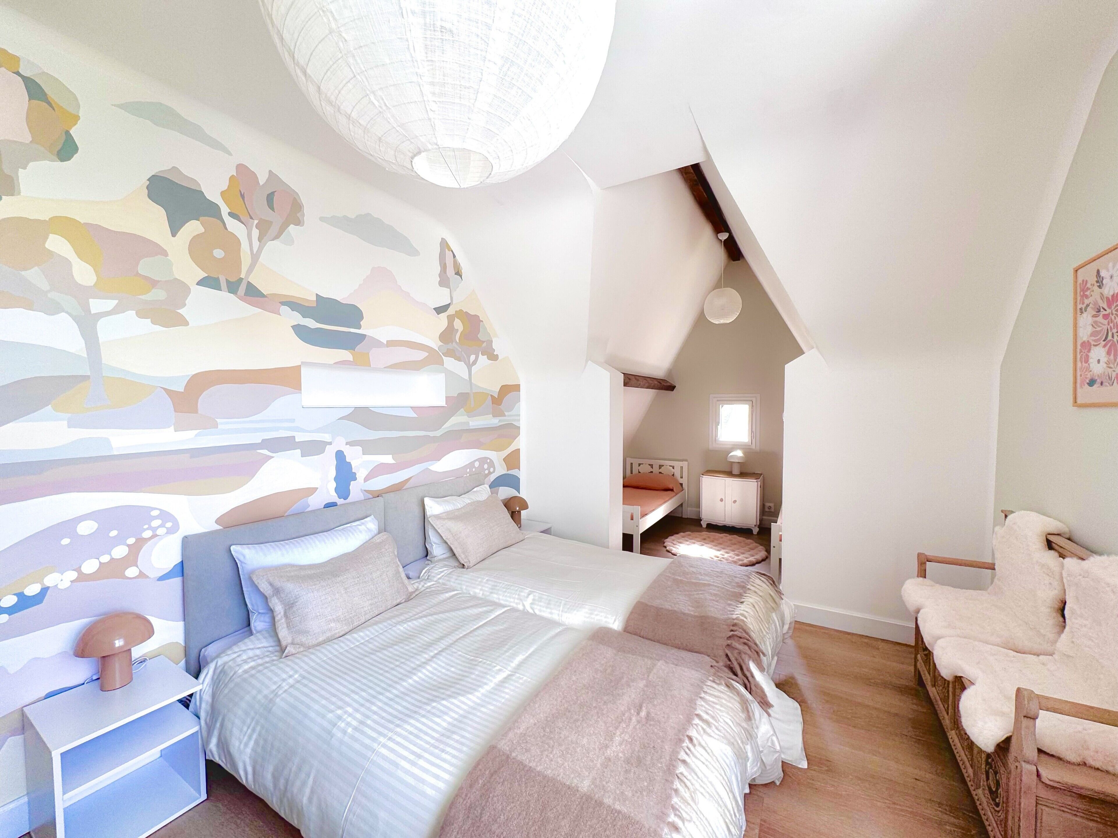 Een slaapkamer met een bed, nachtkastjes, een stoel, een lamp en een muurschildering.