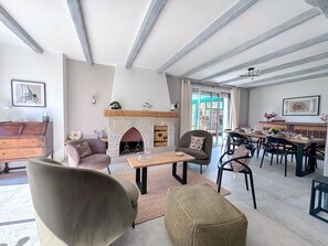 Ein Wohnzimmer mit Kamin, Essbereich und Blick ins Freie.