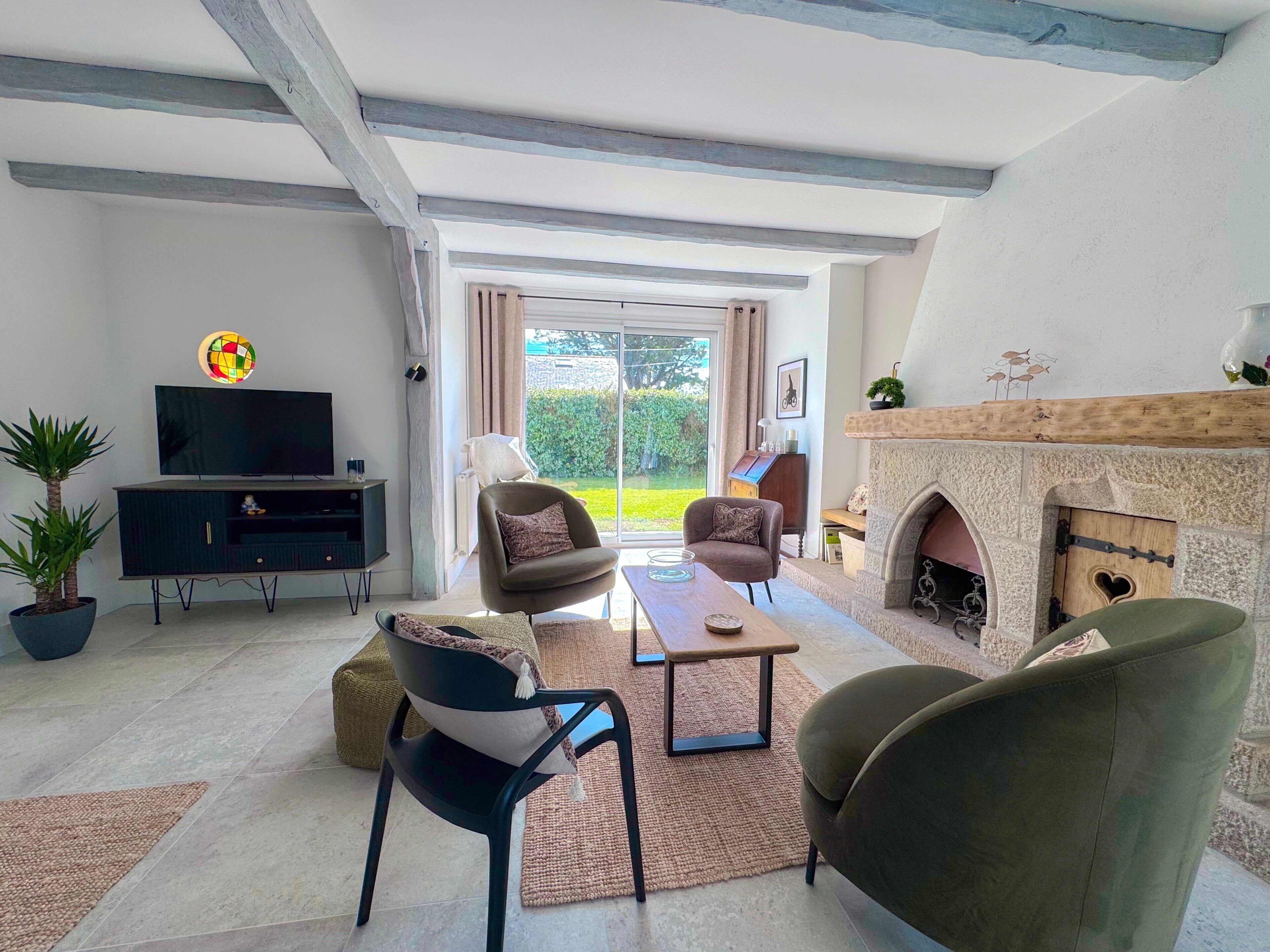 A living room with a fireplace, a television, and a view to the outdoors.