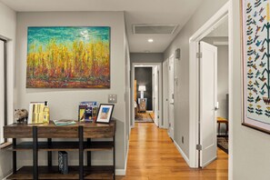 A hallway with a wooden table, books, a bottle, and a painting. - Sedona Wellness Retreat: Gym + Sauna + Steam + Tub (Sedona)