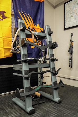 A gym with a weight machine, a flag, and a map on the wall. - Sedona Wellness Retreat: Gym + Sauna + Steam + Tub (Sedona)