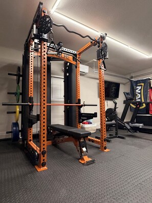 A gym with a squat rack, bench, and various weight plates. - Sedona Wellness Retreat: Gym + Sauna + Steam + Tub (Sedona)