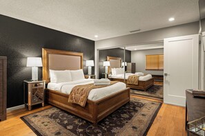A hotel room with a large bed, bedside tables, a mirror, and a wooden floor. - Sedona Wellness Retreat: Gym + Sauna + Steam + Tub (Sedona)