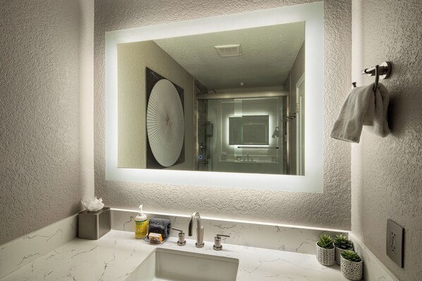 A bathroom with a large mirror, a sink with a marble countertop, a towel rack, and potted plants. - Sedona Wellness Retreat: Gym + Sauna + Steam + Tub (Sedona)