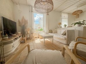 A cozy living room with a television, sofa, coffee table, and a dining area.