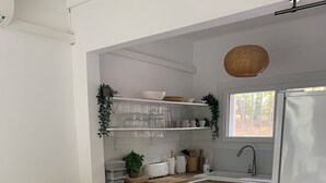 Eine moderne Küche mit weißen Schränken, einem eingebauten Backofen, einem Kühlschrank und einem Essbereich mit einem weißen Tisch und Stühlen.