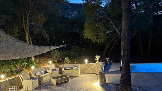 Eine Außenpatio mit Sitzgelegenheiten, einem Pool und einer Steinsäule.