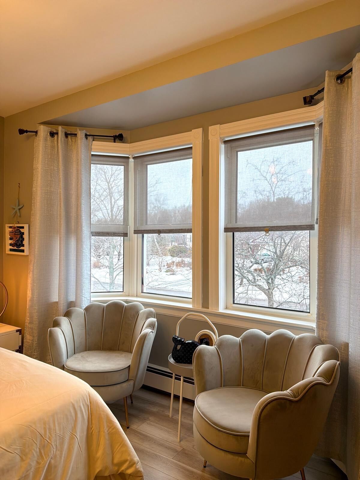 Een kamer met een bed, twee fauteuils, een tafeltje en een raam met uitzicht op een besneeuwd landschap.