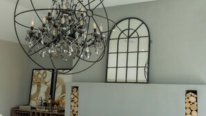 Een woonkamer met een open haard, een kroonluchter en een salontafel met decoratieve objecten.