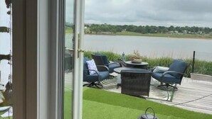 Uitzicht door een glazen deur op een terras met een tafel, stoelen en een lantaarn.