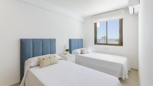 A hotel room with two beds, a window with a view of the beach, and a white color scheme. - AG DUPLEX 2-3 PREMIUM - only families (Playa de Gandía)