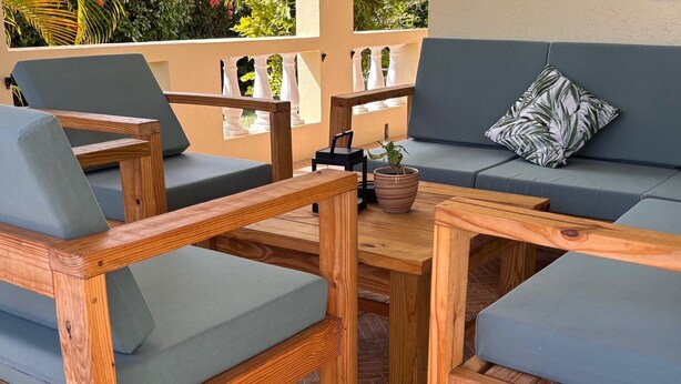 A patio with a sofa, chairs, and a wooden table. - 3-bedroom home away from home near Oistins (Christ Church)
