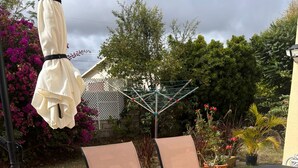 A patio with a metal table and chairs, surrounded by potted plants and a white fence. - 3-bedroom home away from home near Oistins (Christ Church)