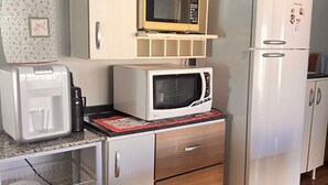 Eine kompakte Küche mit Mikrowelle, Toaster, Kühlschrank und einer kleinen Arbeitsfläche.