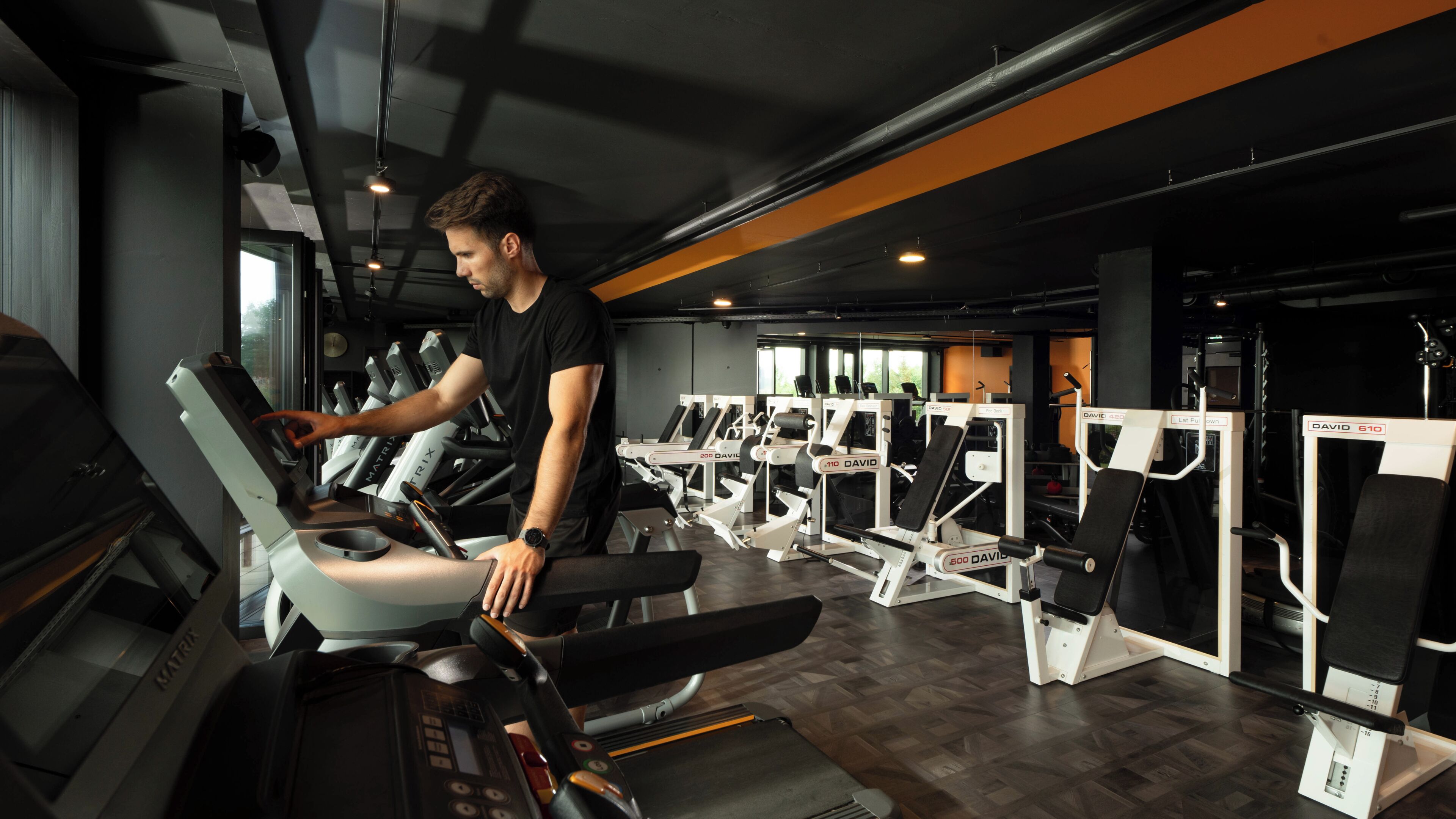 Un gimnasio con cintas de correr, máquinas de pesas y una persona usando una cinta.