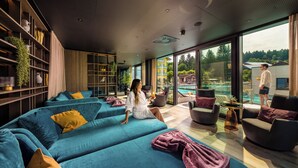 Una sala moderna con un sofá grande, un balcón con vista a la piscina y un ventanal amplio.