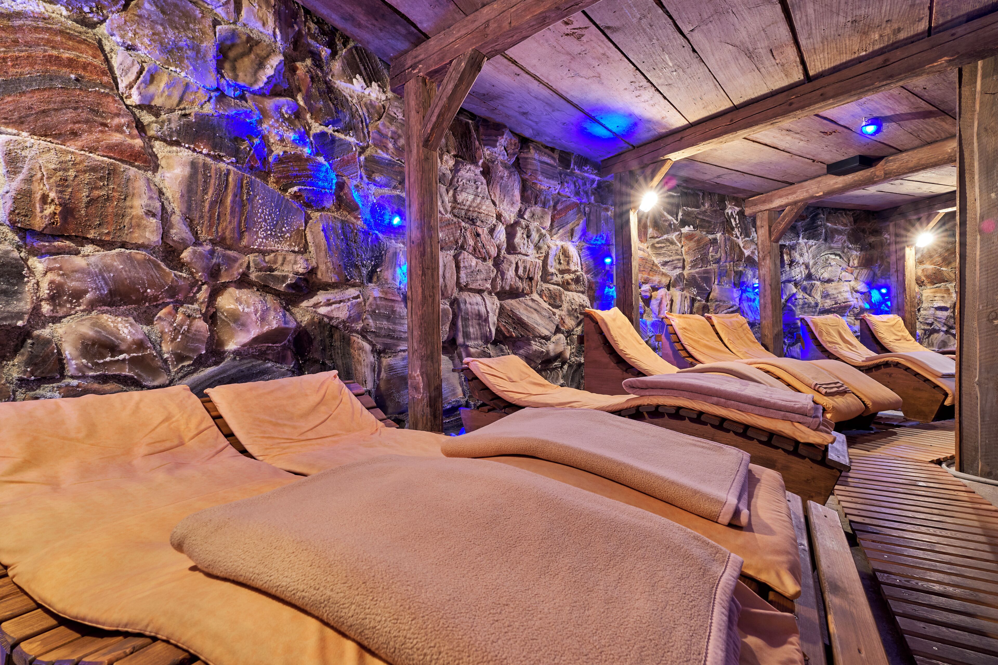 A stone-walled room with wooden benches and beige towels.