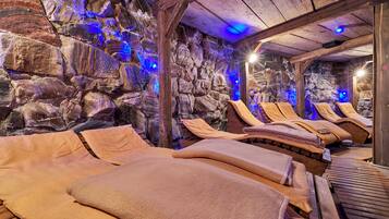 A stone-walled room with wooden benches and beige towels.
