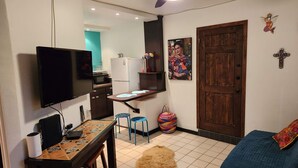 Un espace de vie compact comprenant un coin cuisine, un téléviseur, un canapé et une porte.