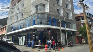 Um edifício com vários andares, fachada de vidro, entrada no andar térreo e uma placa com a inscrição 'RENIEC'.