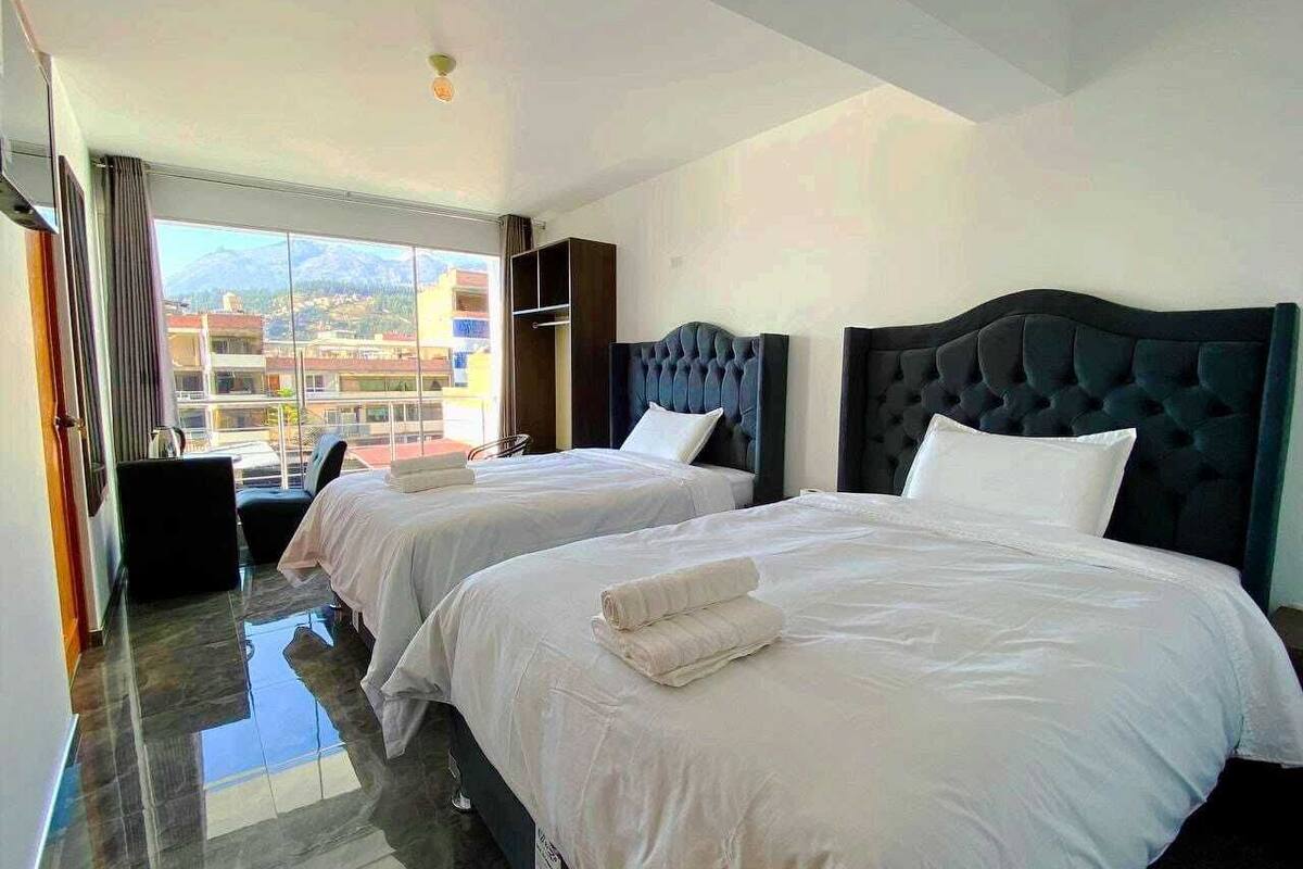 A hotel room with two beds, a view of mountains, and a balcony.