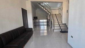 Um corredor com um sofá, escada e porta que dá para um quarto.