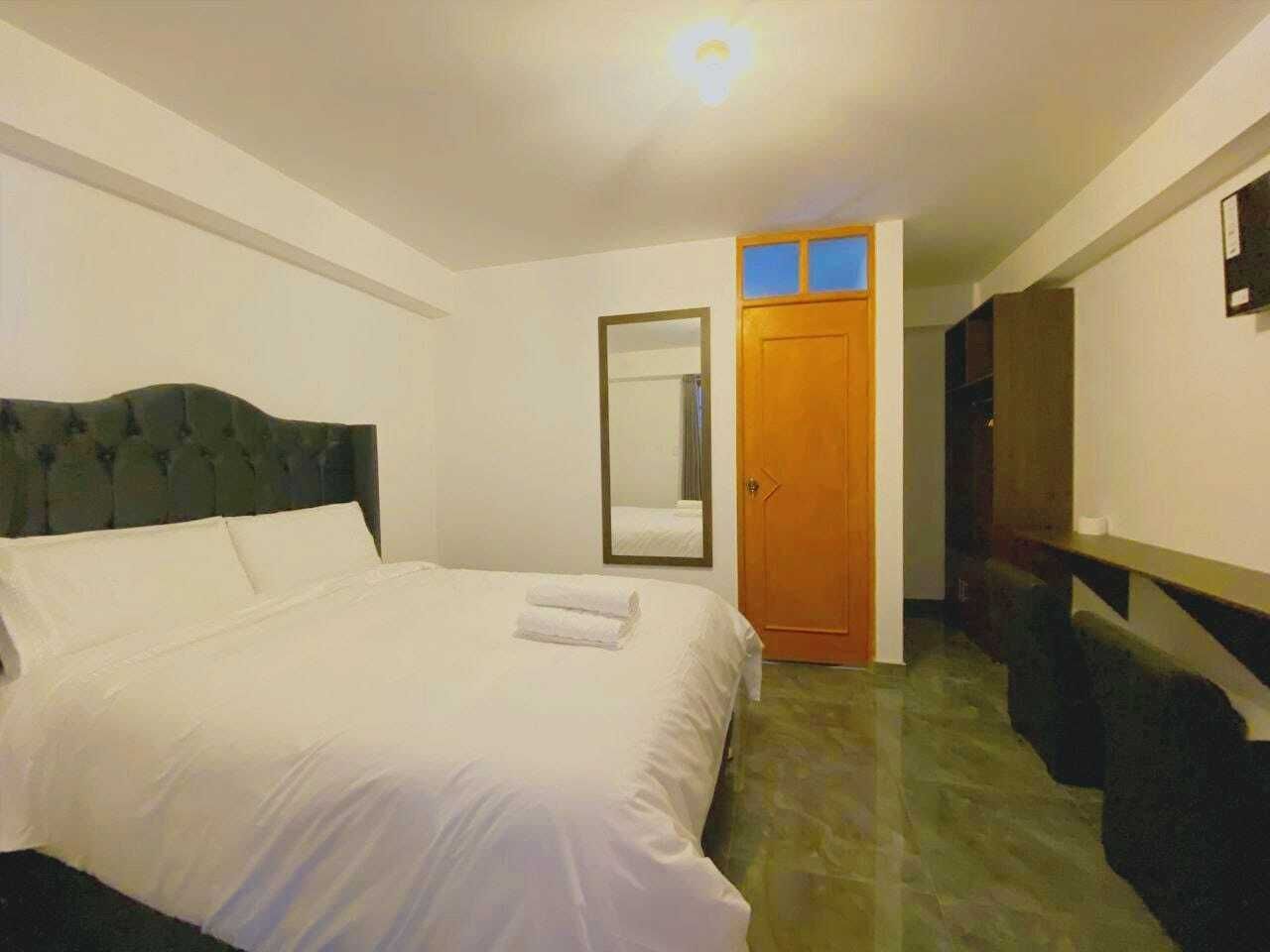 A bedroom with a bed, a mirror, a wooden door, and a staircase.