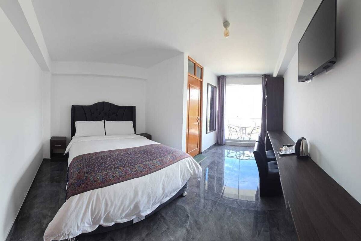 A hotel room with a bed, a desk, a chair, and a TV.