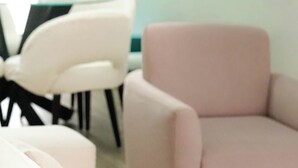 Ein modernes Wohnzimmer mit einer Couch, Sesseln und einem Esstisch.