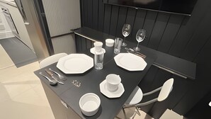 A modern dining area with a black table set for two, including plates, cutlery, and glasses. - Clementino 210 (São Paulo)