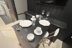 A modern dining area with a black table set for two, including plates, cutlery, and glasses. - Clementino 210 (São Paulo)
