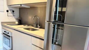A modern kitchen with stainless steel appliances, a double sink, and integrated oven. - Clementino 210 (São Paulo)