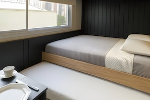 Um quarto pequeno e moderno, com cama, mesa de cabeceira e janela.