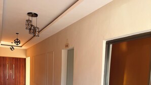 Un pasillo moderno con un revestimiento de madera, una puerta de cristal e iluminación geométrica en el techo.