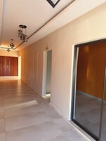 Un pasillo moderno con un revestimiento de madera, una puerta de cristal e iluminación geométrica en el techo.