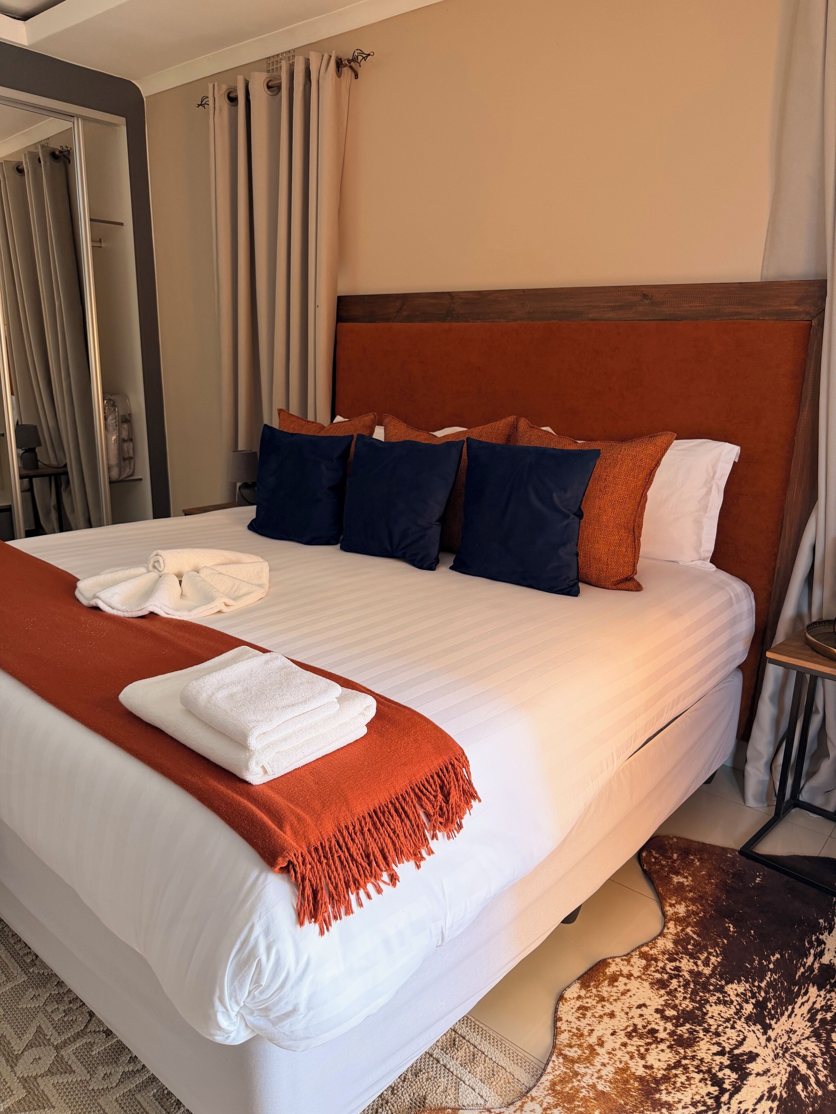 A hotel room with a large bed, a wooden headboard, and a patterned rug.