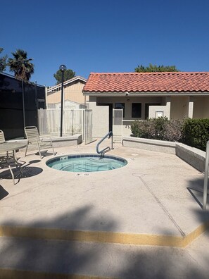 A swimming pool with a hot tub, surrounded by a fenced area with lounge chairs and a building with a red-tiled roof. - Vegas Hideaway conveniently located from airport and strip 8-20 minutes. . . (Las Vegas)