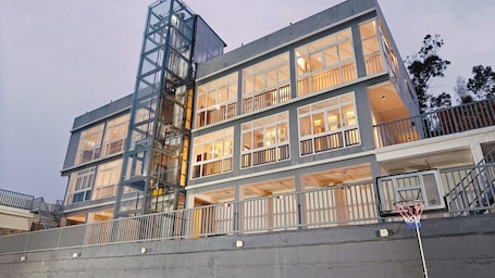 A multi-story building with balconies, a visible elevator, and a basketball hoop.