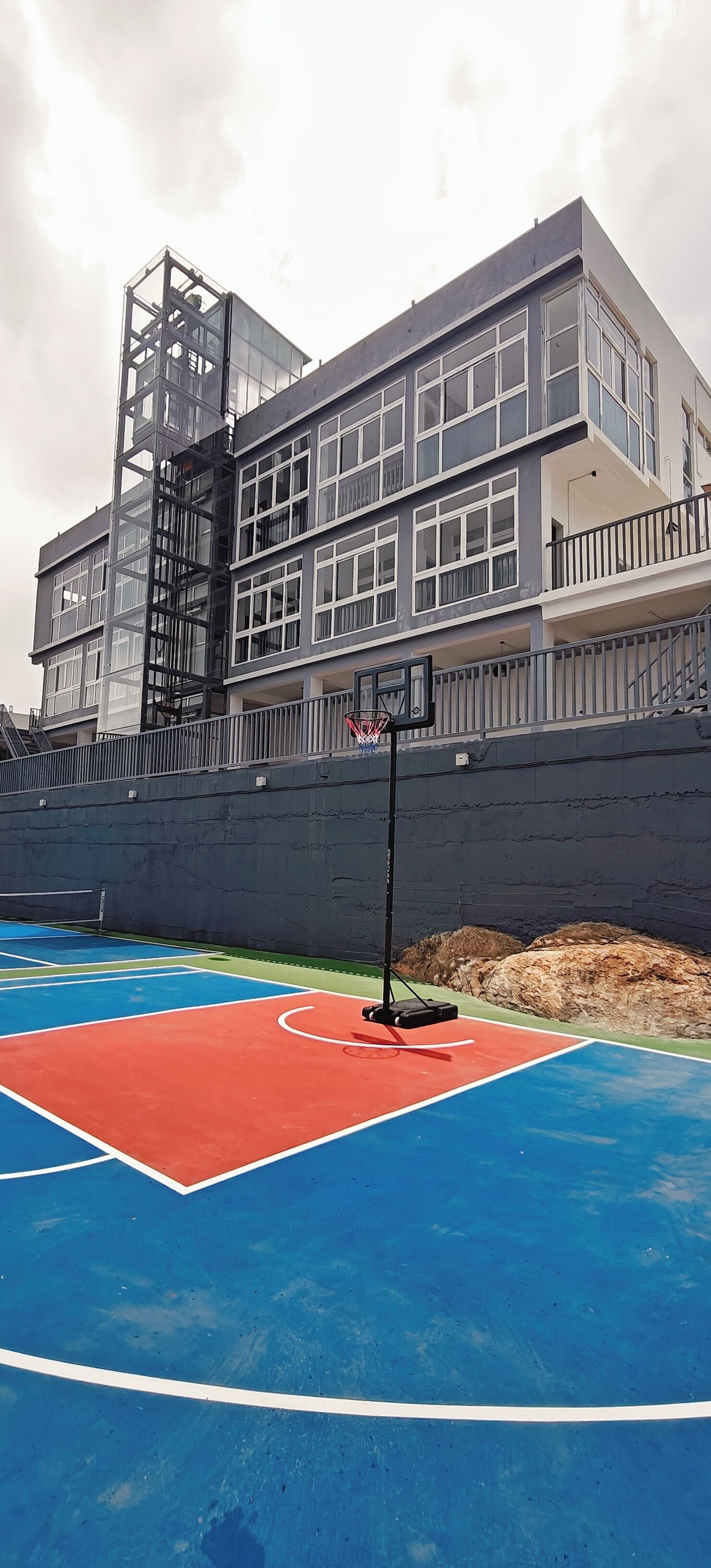 An outdoor basketball court with a building in the background.