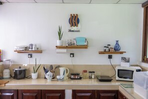 A kitchen with wooden cabinets, a blender, a kettle, and various kitchen utensils on the counter.