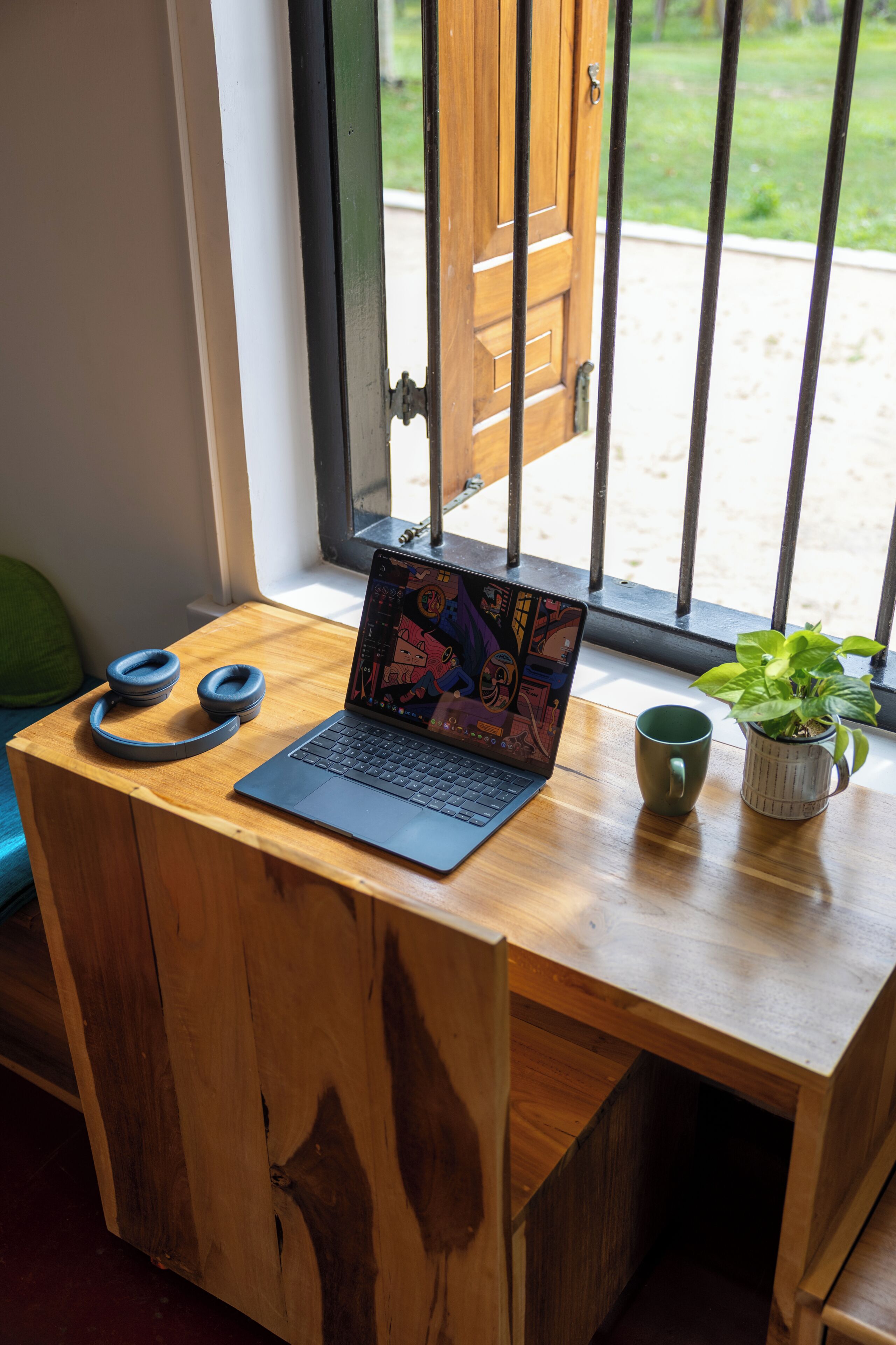 Una computadora portátil sobre un escritorio de madera, con una ventana y una puerta al fondo.