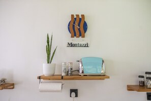 A wall-mounted shelf with a potted plant, a toaster, and a clock.