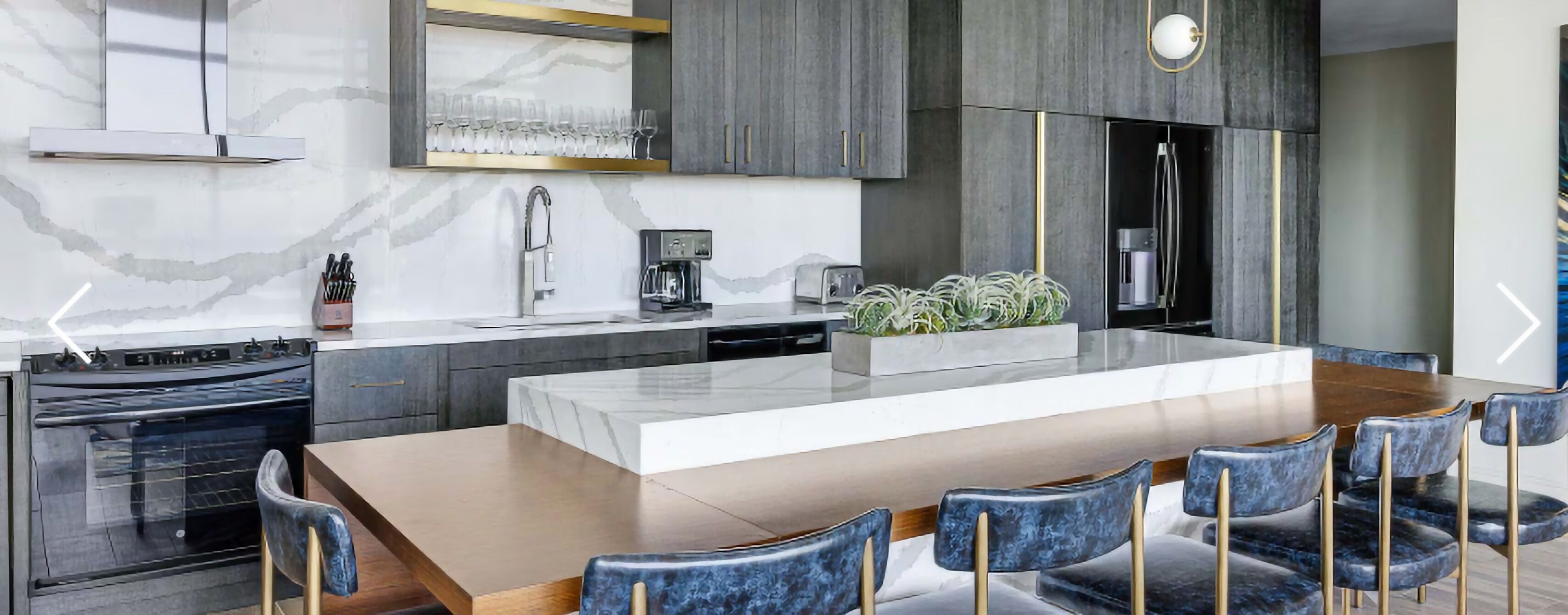 A modern kitchen with a central island, a built-in oven, and a coffee machine.