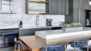 Una cocina moderna con una isla central, horno empotrado y cafetera.
