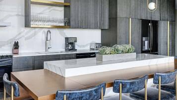 A modern kitchen with a central island, a built-in oven, and a coffee machine.